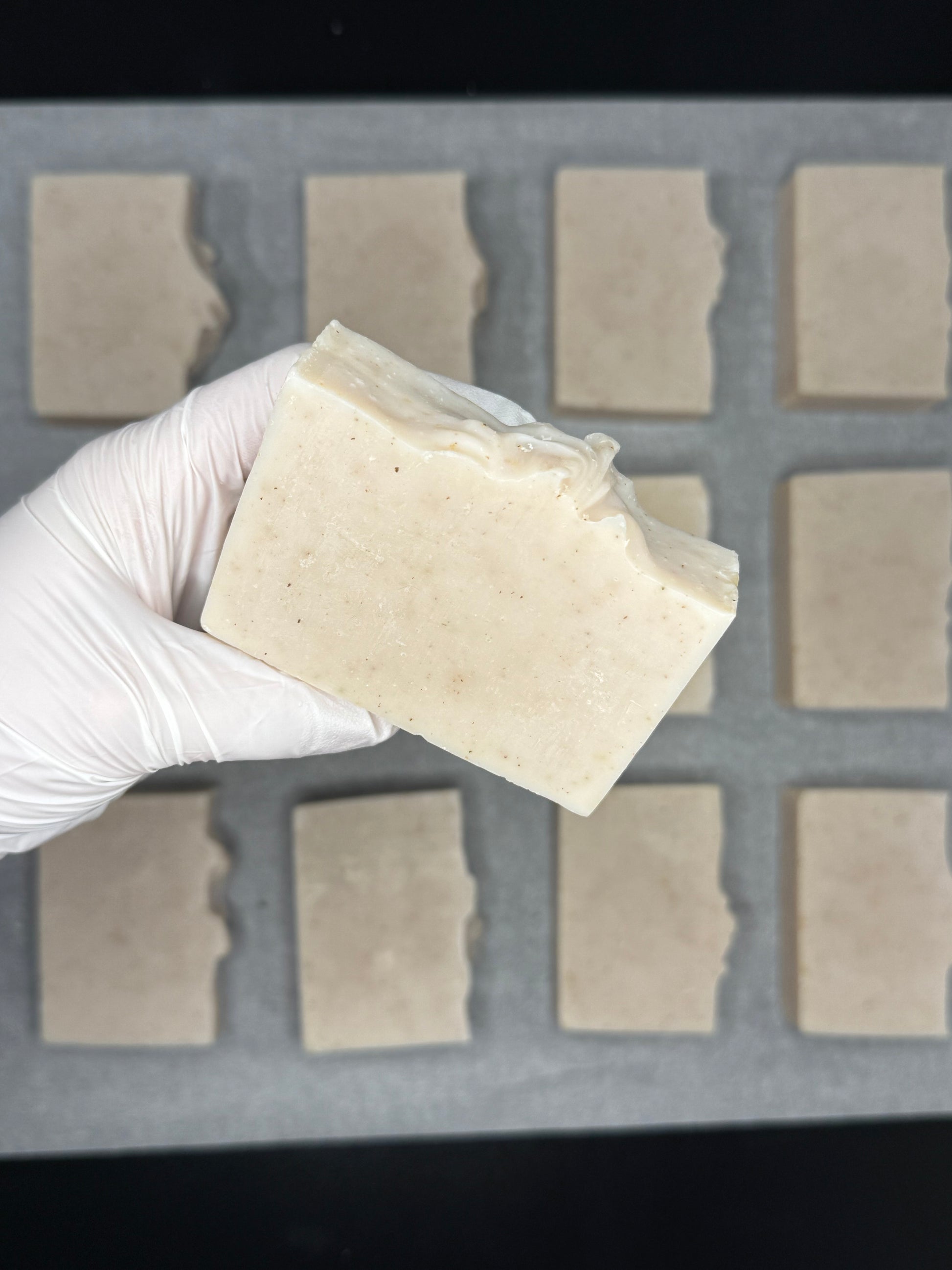Hand wearing a white glove holding a block of tofu in front of a grid of square blocks.