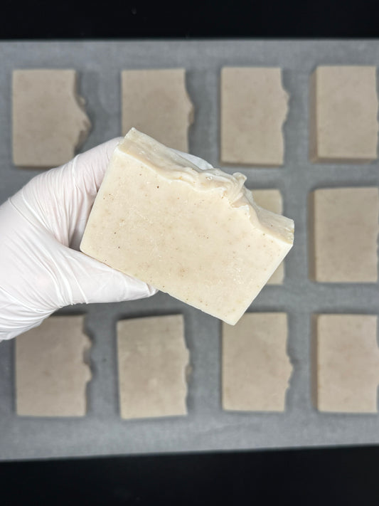 Hand wearing a white glove holding a block of tofu in front of a grid of square blocks.