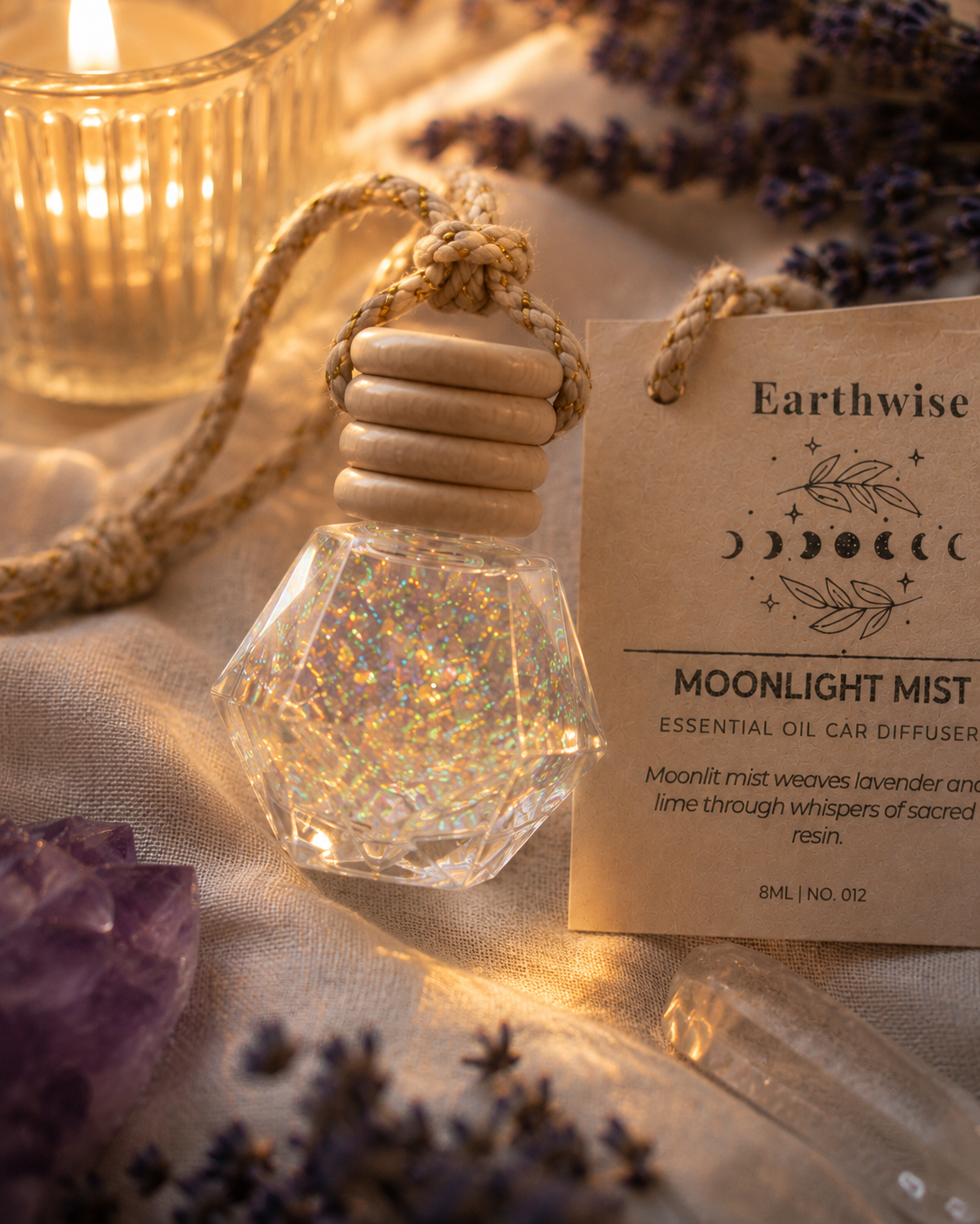 Crystal car diffuser with 'Earthwise' label on a soft fabric background with lavender flowers.
