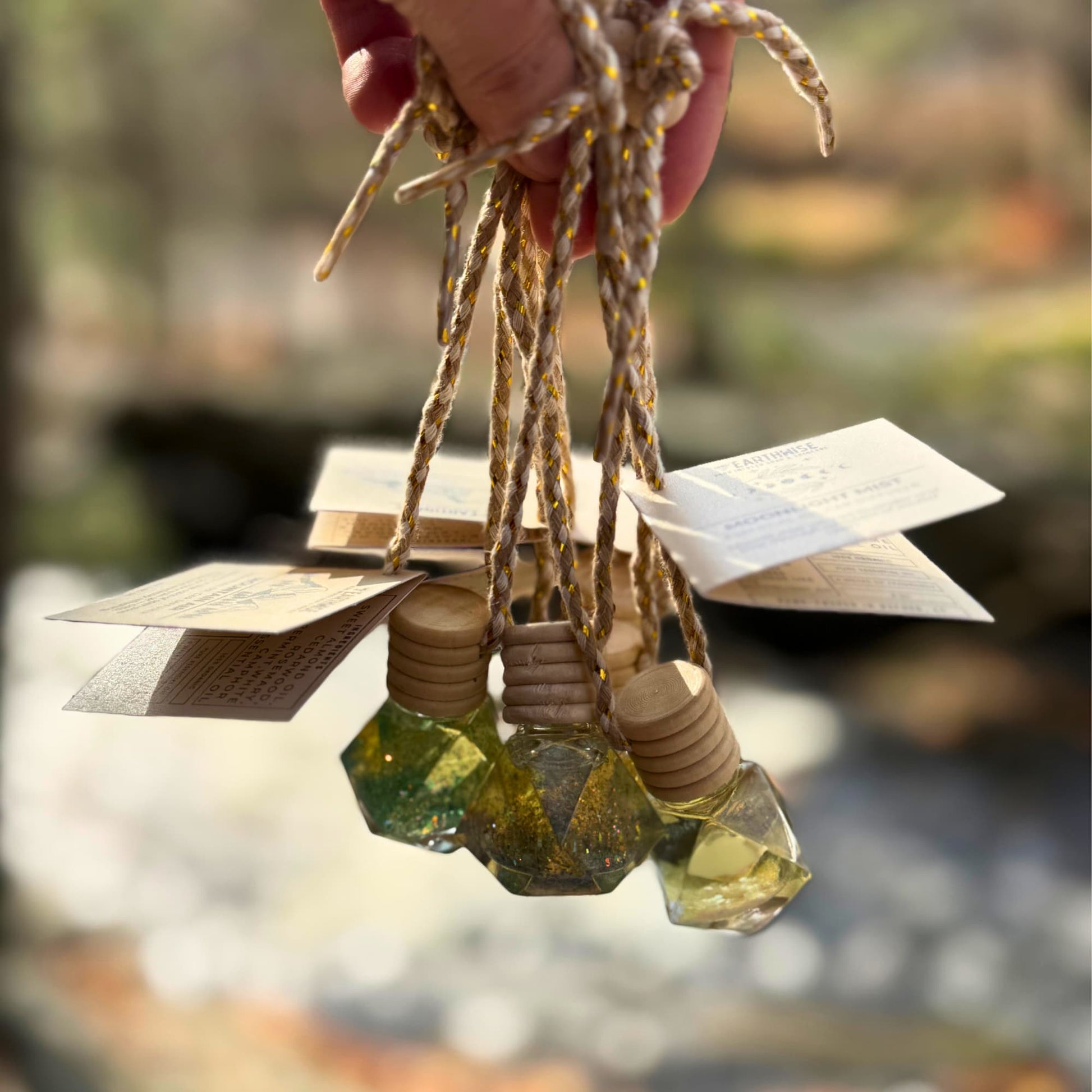 Hand holding natural essential oil car diffusers made of glass geometric shapes and glitter