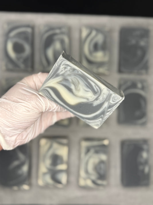 Hand holding a soap with black and white swirls
