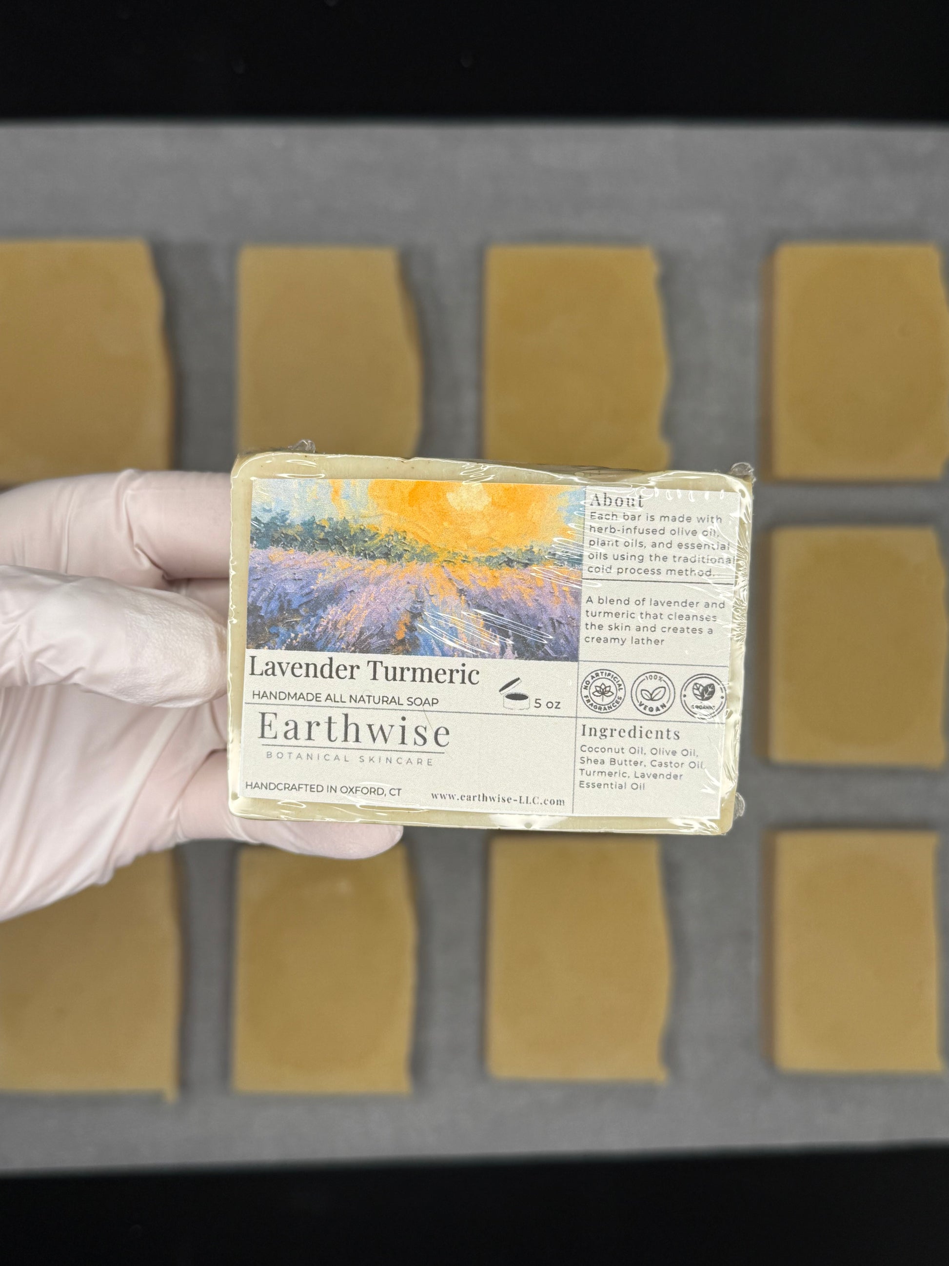 Bar of soap with a label held by a gloved hand against a gray background