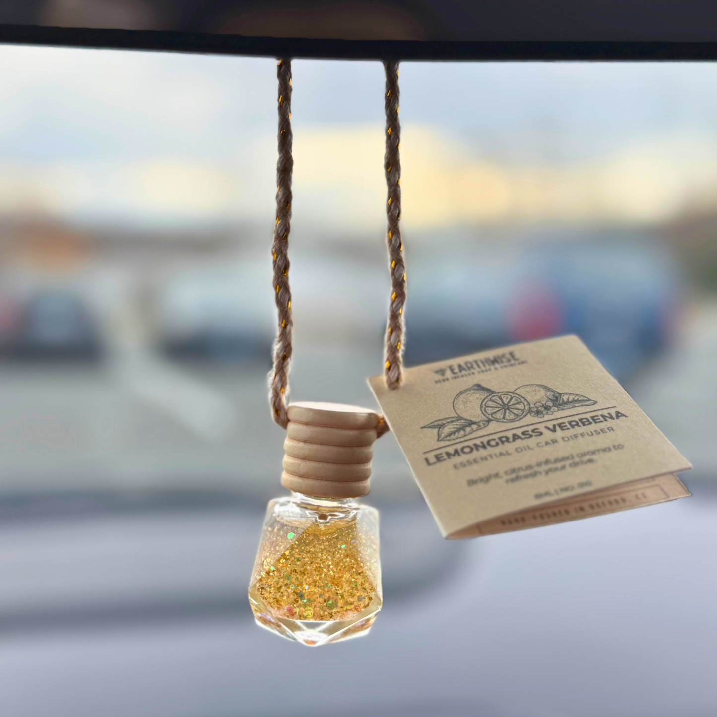 Car air freshener with lemon grass verbena scent hanging inside a car.