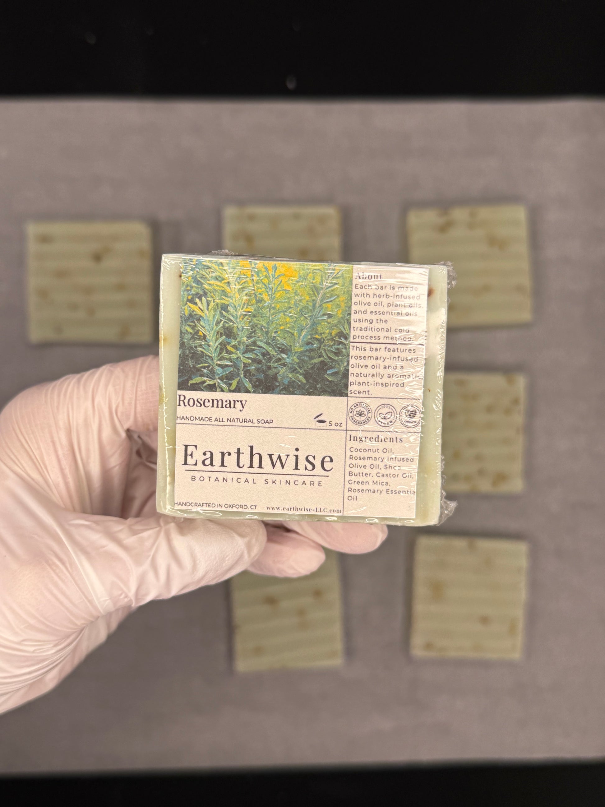 Hand holding an Earthwise soap bar with a label, against a neutral background