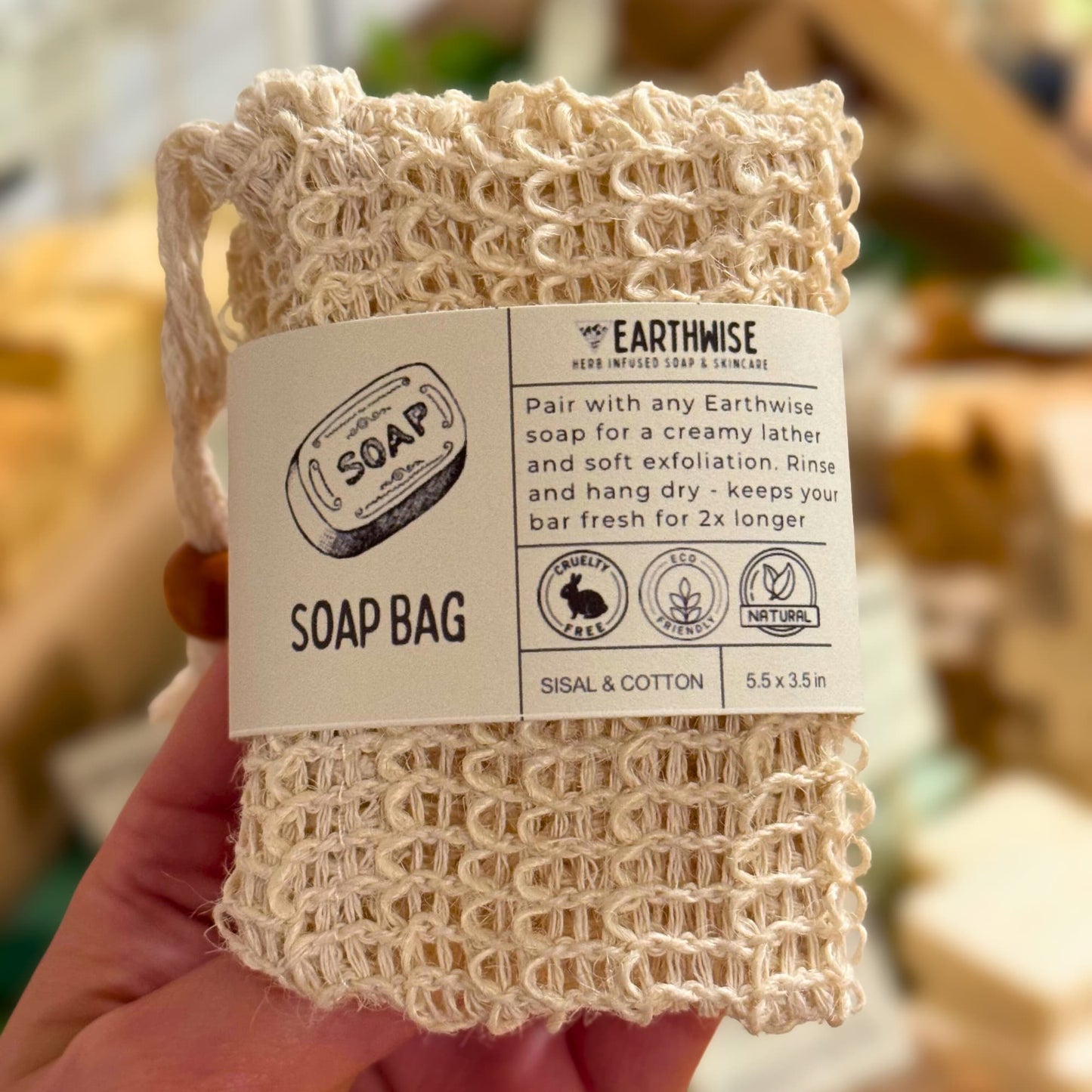 Earthwise natural exfoliator soap bag held in a hand with a blurred background