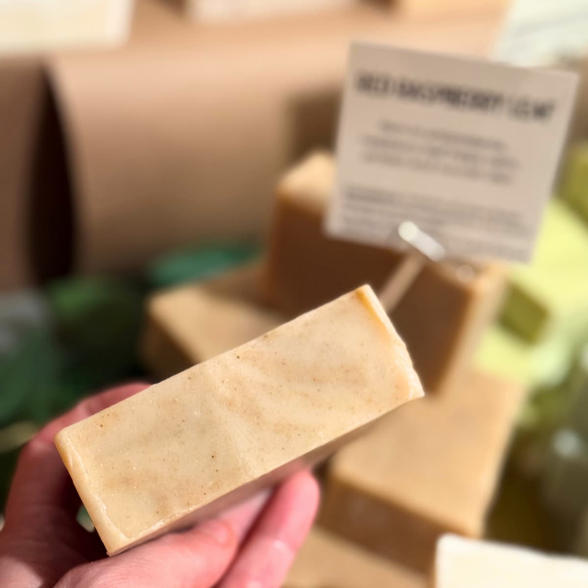 Herbal bar of soap held in a hand with a blurred background