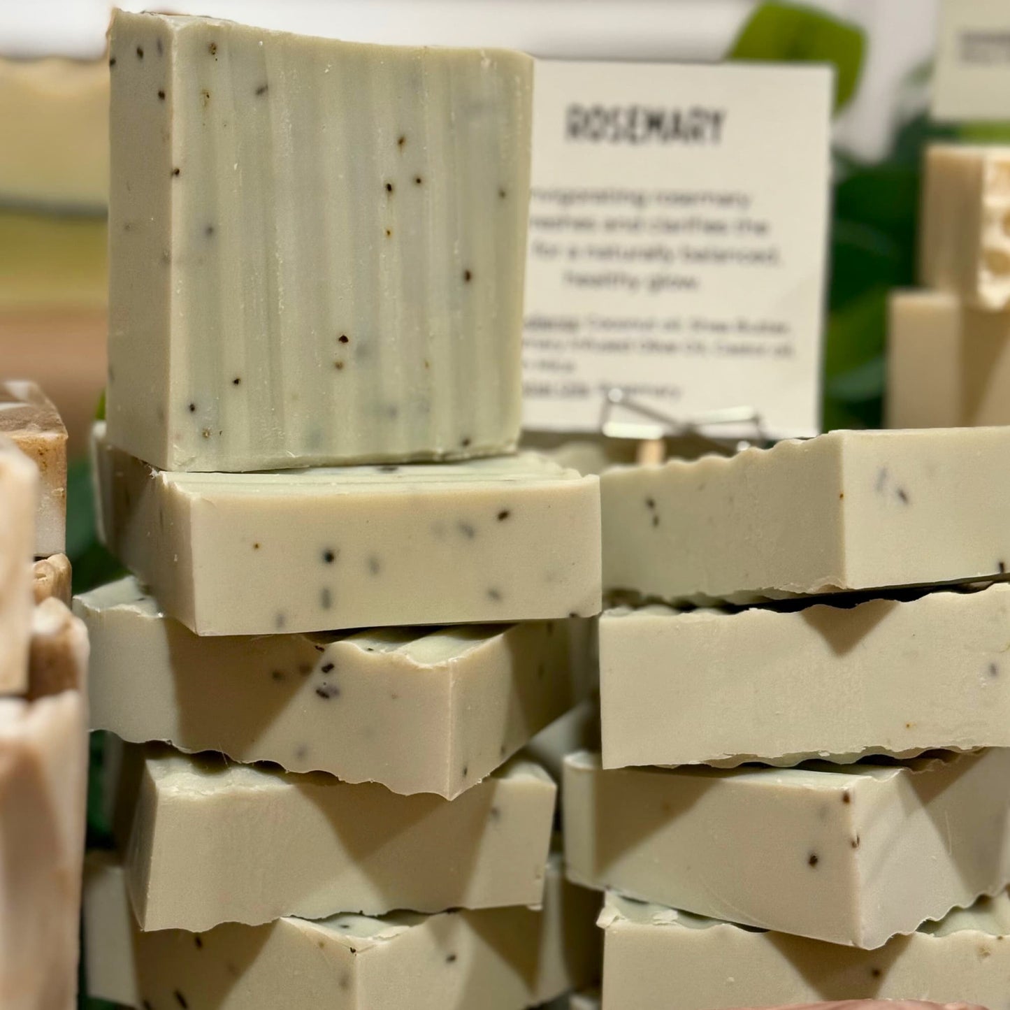 Stack of rosemary herbal soap bars with a visible label in the background