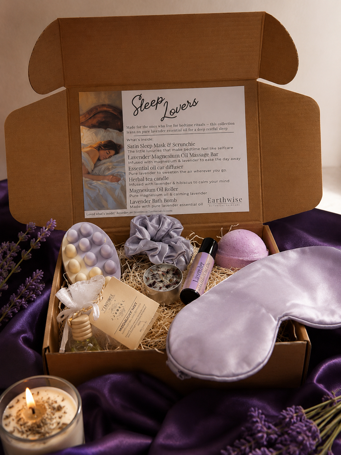 A sleep lovers gift box surrounded by purple satin sheets and lavender products