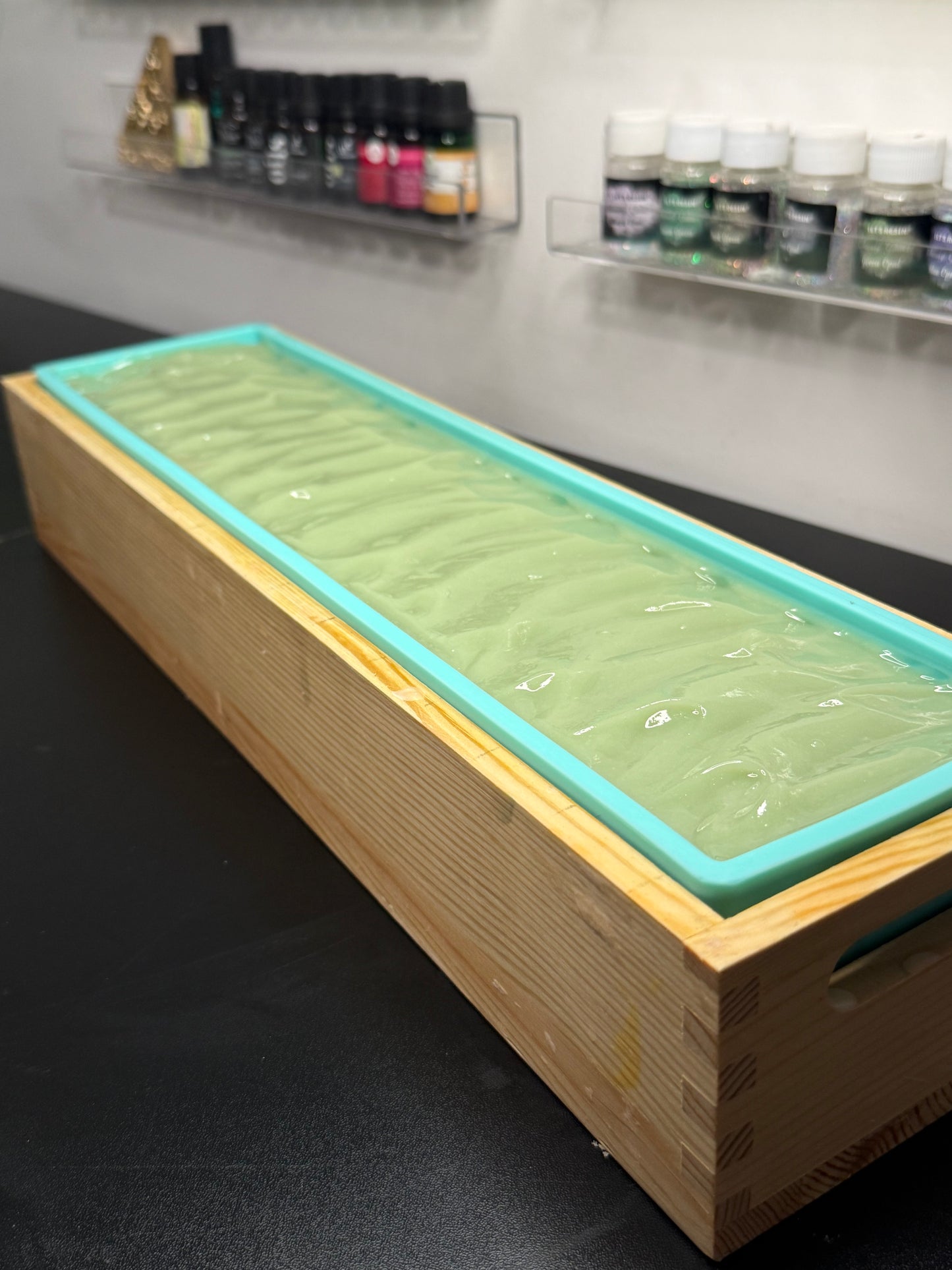 Wooden box with a green cold process soap on a dark surface