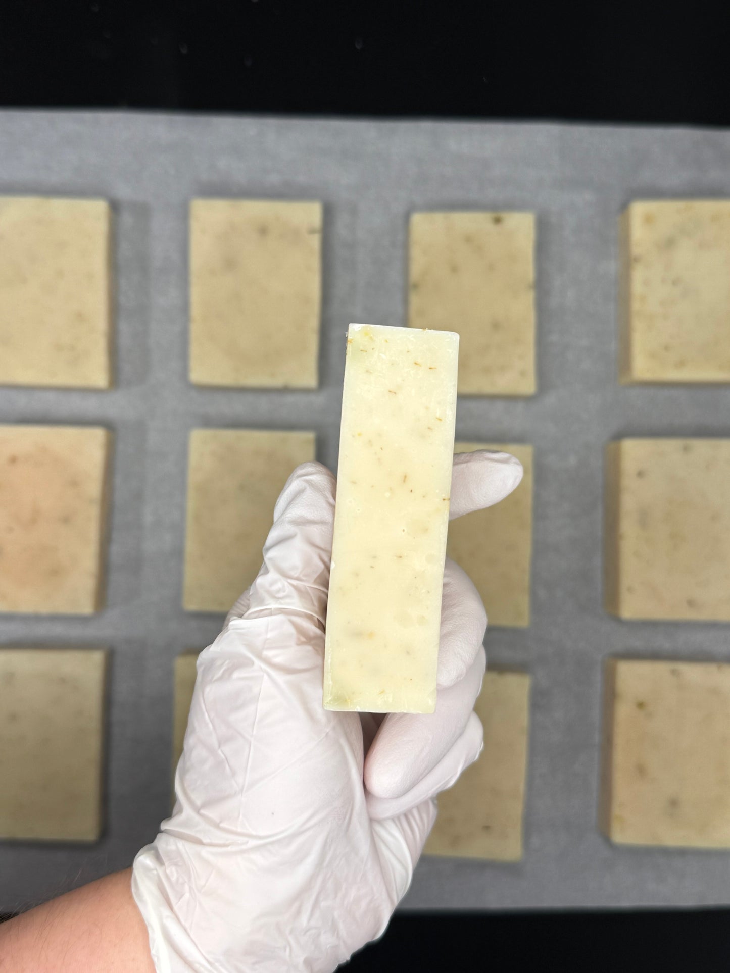 Hand holding an organic herbal soap bar against a grid background