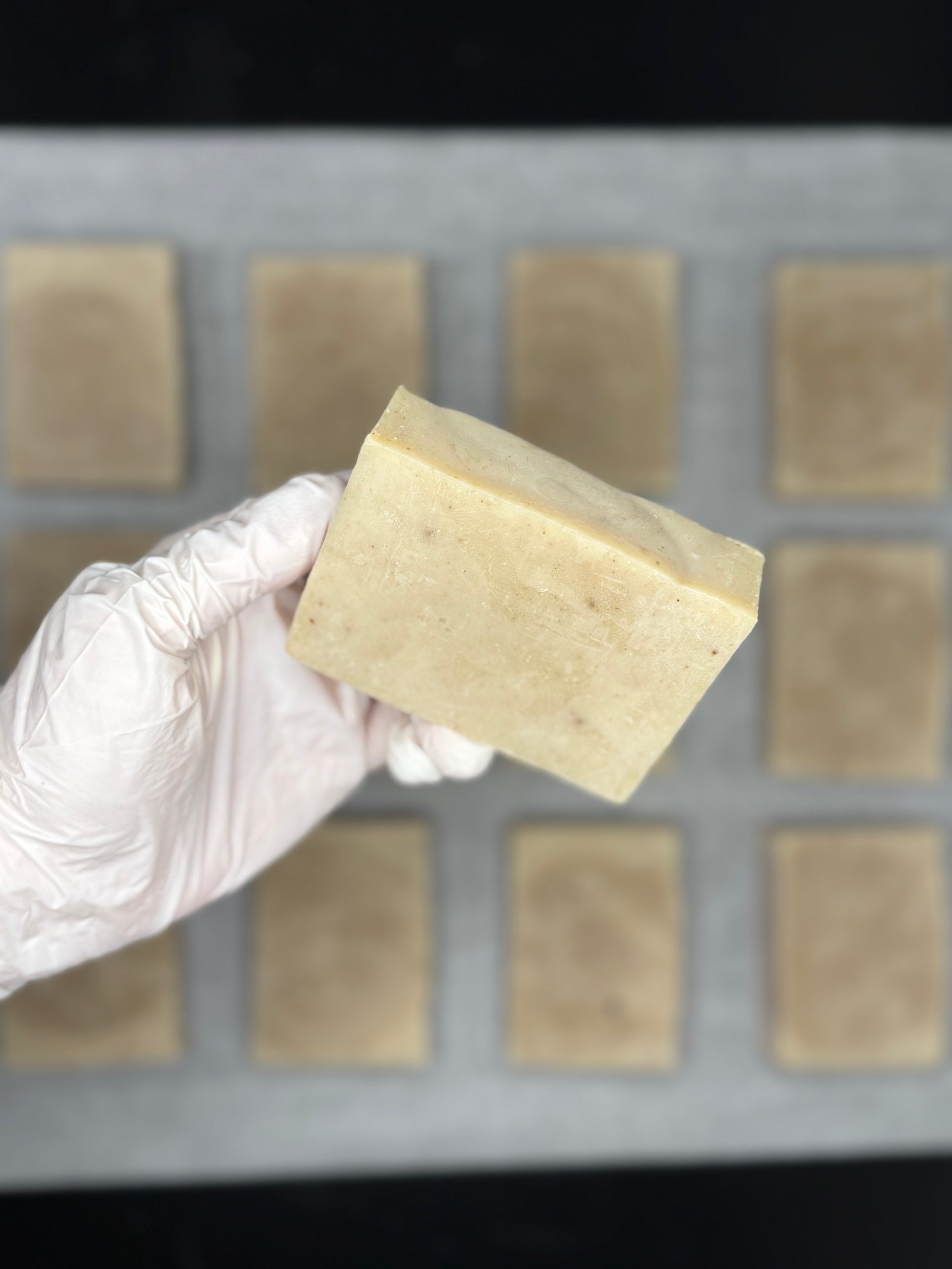 Hand holding a block of soap above a tray with more soap blocks.